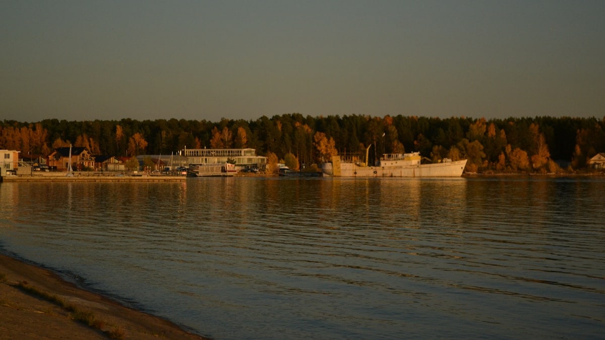 a body of water with a building and trees in the background